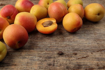 Fresh ripe juicy yellow orange red apricot fruit pile whole cut half slice seed on rustic wood background flat lay top view border frame copy text space