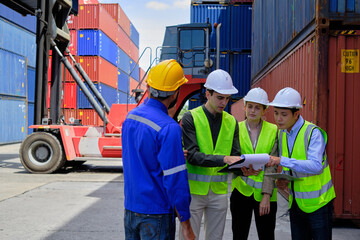 A Group of multiracial workers people in safety uniforms and hardhats work at logistics terminal with many stacks of containers, loading control shipping goods for the cargo transportation industry.