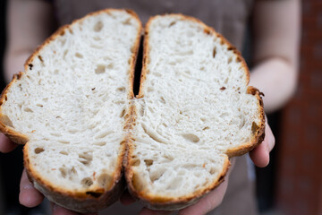 The baker shows a cut of the finished artisan bread. The process of making bread in the artisan bakery. Front view.