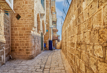 Stone narrow streets of the Old City of Jaffa against blue sky with clouds