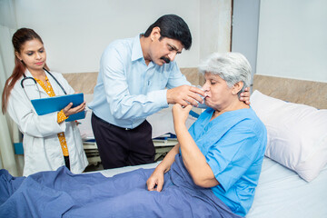 Obraz premium Indian son heal her old mother drink water at hospital bed, Senior patient at clinic, Elderly people health care. care giver.