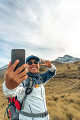Fototapeta premium Happy latin man hiker taking a selfie on mountain edge in mexico