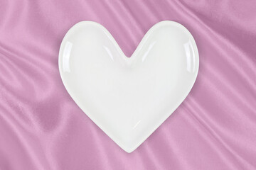 White Heart Shaped Plate on Elegant Pink Silk Background