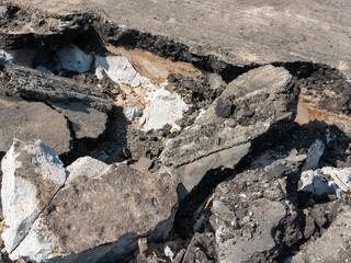 Close-up. Pieces of old broken asphalt with big stones. Road repair