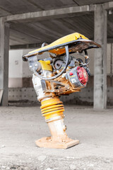 Vibratory rammer with vibrating plate on a construction site. Compaction of the soil before laying...