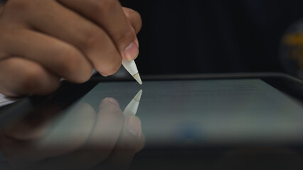 Close up hand of business person sign the signature on the contract agreement document on free right space tablet computer in the office. Cyberspace technology concept.