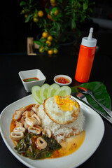 Stir Fried Basil with Squid with Rice or seafood fried rice with basil Thai food on black table, hot and spicy
