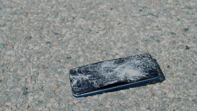 Close up view of smartphone being run over and crushed by vehicle