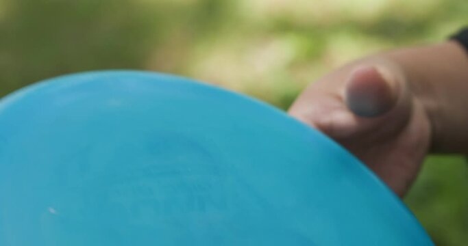 Close up shot of man throwing blue disc golf.
