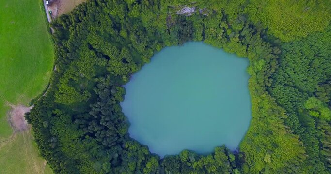 Aerial drone view of lagoa do Congro blue turquoise round lake in middle of green countryside