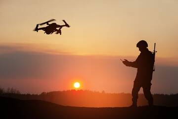 Obraz na płótnie Canvas Silhouette of soldier are using drone and laptop computer for scouting during military operation against the backdrop of a sunset. Greeting card for Veterans Day, Memorial Day, Independence Day.