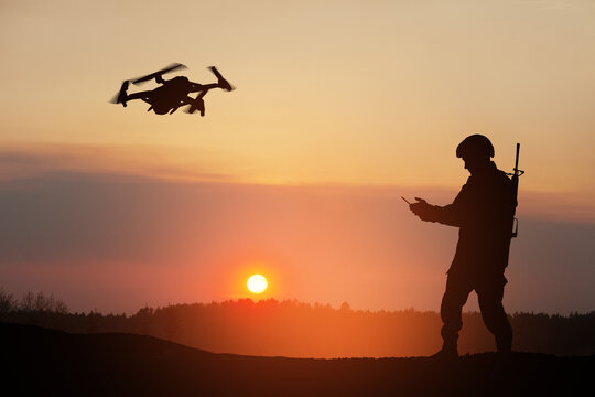 Silhouette of soldier are using drone and laptop computer for scouting during military operation against the backdrop of a sunset. Greeting card for Veterans Day, Memorial Day, Independence Day.
