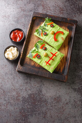 Funny kids burrito monster with sauces on a wooden tray on the table. halloween food. vertical top view from above