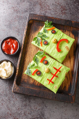 Halloween party Children's food monster burritos with sauces on a wooden tray on the table. Vertical top view from above