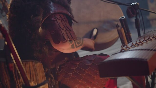 Performer plays old leather shamanic drum with special furry stick at concert in old cabin closeup. Musician plays ritual music. Folk band