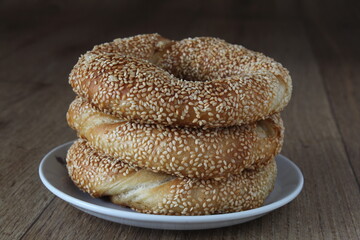 Turkish bagel with sesame seeds and butter in white plant on kitchen table. Known as ‘tereyagli simit’ in Turkish.

