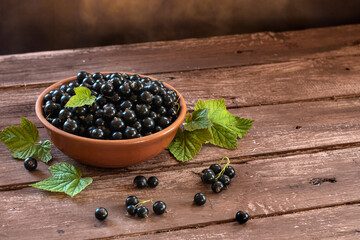 Fototapeta na wymiar Black currant in a bowl isolated on a wooden background. Blackcurrant berries.