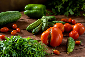 Fresh vegetables on a wooden table. Tomatoes, cucumbers, sweet peppers, parsley, dill.