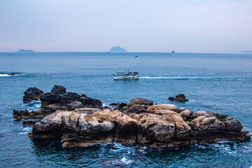 Fishing vessel sails past cliffs in the sea near Yeh Liu, Taiwan