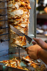 Chef cutting with doner knife Traditional Turkish Doner Kebab meat.