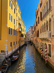 Traditional narrow canal with gondola and bridge in Venice, Italy. Architecture and landmark of Venice. Cozy cityscape of Venice.