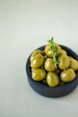 Juicy ripe olives in a wooden plate with a thyme branch