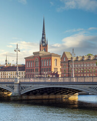 Old National Archive, or Gamla Riksarkivet, and the Norstedt Buildings, overlooking Vasabron or Vasa bridge and Norrstrom River, with tower of Riddarholmen Church in the background, Stockholm, Sweden