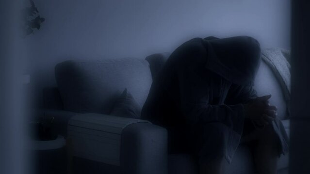 Evanescent scene of a depressed man in a bathrobe on the couch. Black and white. Static view