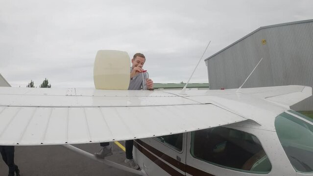 Pilot Measures Fuel Of A Cessna Plane, Dipping Fuel Stick Into Fuel Tank Mounted On The Wing. wide