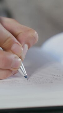 Close-up of a writing with a pen in a notebook female hand