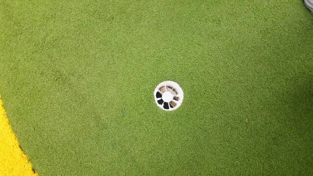 golf ball going in hole top view stroke putt in hole