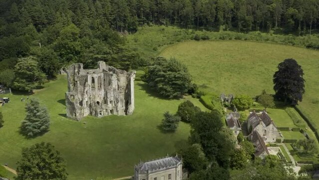 View over Old Wardour Castle in a forest setting with bright green sunny fields.