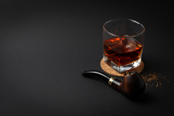 Smoking pipe, tobacco and glass of alcohol on black background