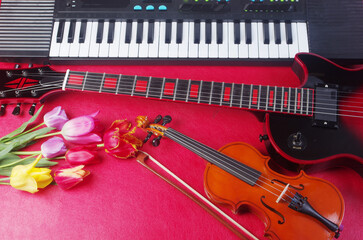 Electric guitar, violin, synthesizer keyboard and a bouquet of tulips and lilies of the valley on a...