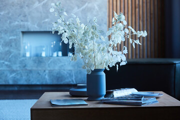 A table with magazines and a frosted vase with dried flowers. Stylish modern decor. Loft-style interior design.