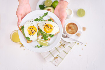 healthy breakfast or snack - sliced avocado and fried egg on toasted bread and cup of coffee