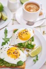 healthy breakfast or snack - sliced avocado and fried egg on toasted bread and cup of coffee