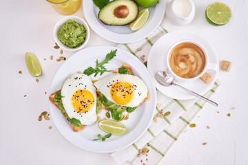 healthy breakfast or snack - sliced avocado and fried egg on toasted bread and cup of coffee
