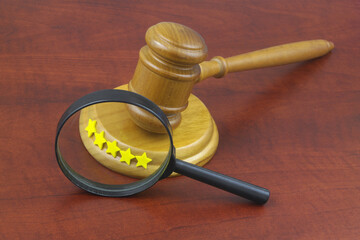 Check quality on legal service concept. Wooden gavel with five stars under magnifying glass.