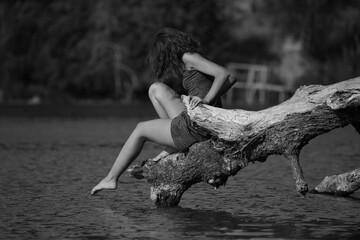 Barefoot young woman playing with water in the lake in black and white