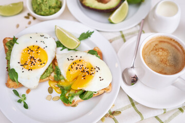 Fototapeta na wymiar healthy breakfast or snack - sliced avocado and fried egg on toasted bread and cup of coffee