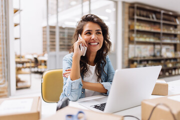 Cheerful businesswoman speaking on the phone in a warehouse