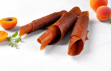 Fruit pastila with apricot and apple. Natural rolled dessert made of dried pureed fruits on white table - 520744257