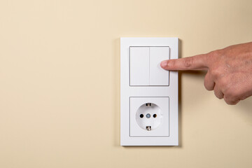 Hand on electrical switch and contact. Concept of electricity consumption, energy saving and prices.