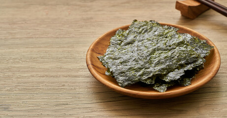 roasted nori laver seaweed snack in wood plate on wooden table background. nori laver seaweed...