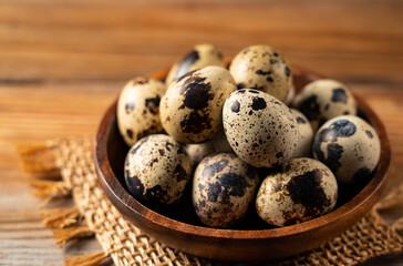 Many quail eggs placed against a wooden background.