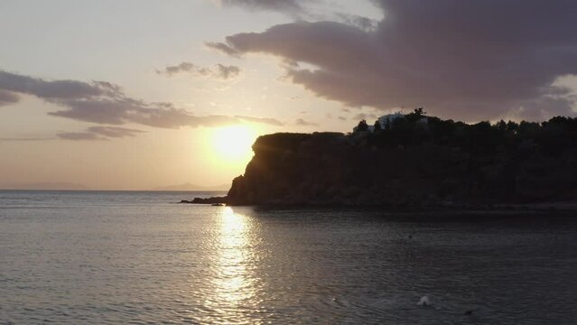 Aerial - sunset reveal behind rocks over the sea