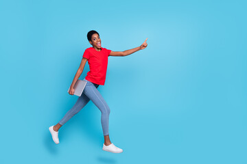 Fototapeta na wymiar Photo of excited positive short hair human wear red t-shirt jumping running holding device empty space isolated blue color background