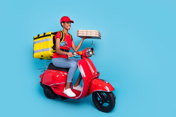 Full length portrait of positive person drive moped hold pizza packages isolated on blue color...