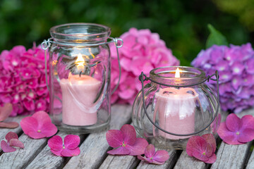 romantisches Arrangement mit Kerzen und pink Hortensienblüten im Garten
